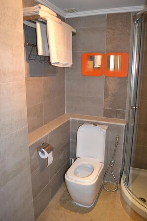 A bathroom with a toilet, a shower, and a towel rack with towels.