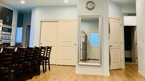 Amplia sala de estar con una mesa y sillas de comedor, una cocina con electrodomésticos modernos y un pasillo que conduce a los dormitorios.