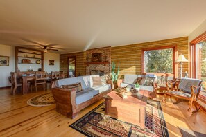 Relax in this spacious living area with a high ceiling, ceiling fan, and comfortable sofa set.