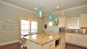 A spacious kitchen with a large island, white cabinetry, and pendant lights. - Luxury in Crystal Beach~ 4/3 ~ Beautiful Beach Views~Direct beach access (Crystal Beach)