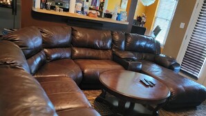 A modern living room with a large L-shaped sectional sofa, a round coffee table, and a patterned rug. - HOME AWAY FROM HOME FOR THE MASTERS (Augusta)