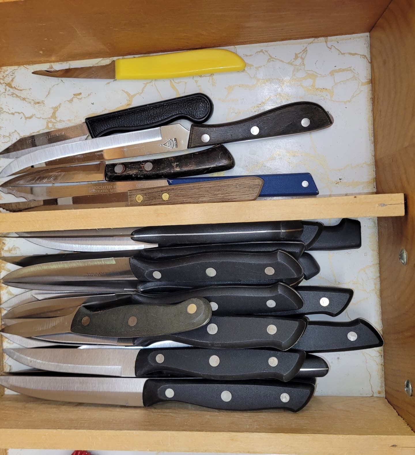 A drawer containing various knives with wooden handles and metal blades, organized on shelves.