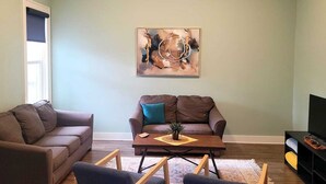 A living room with two sofas, a coffee table, and a painting on the wall.