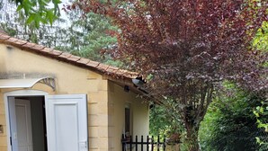 A patio with a barbecue grill, a door, and potted plants. - Studio in Sarlat, for a couple in search of calm (Sarlat-La-Canéda)