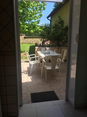 An outdoor patio with a table and chairs, a potted plant, and a stone wall in the background. - Studio in Sarlat, for a couple in search of calm (Sarlat-La-Canéda)