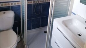 A bathroom with a glass-enclosed shower, a white toilet, and a white sink with a mirror above it. - Studio in Sarlat, for a couple in search of calm (Sarlat-La-Canéda)
