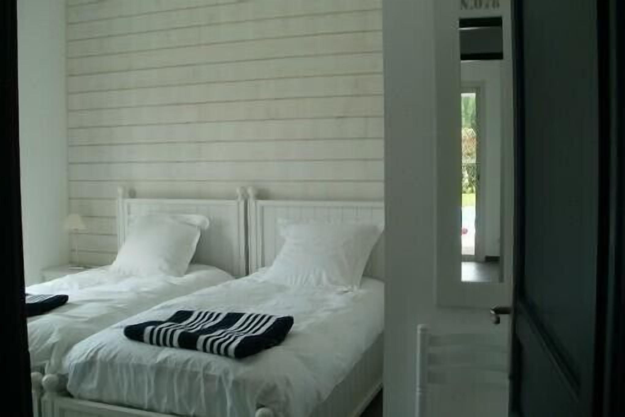 A bedroom with two beds, white bedding, and a striped blanket on one bed.
