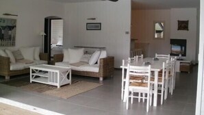 Ein Wohnzimmer mit Sofa, Couchtisch, Esstisch mit Stühlen und Deckenventilator.
