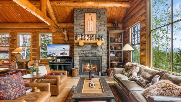 L’intérieur d’un chalet confortable, avec une cheminée, des meubles en bois et un téléviseur.