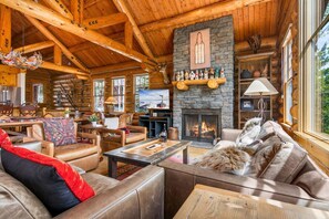 A log cabin interior with a fireplace, leather furniture, a television, and a stone wall.