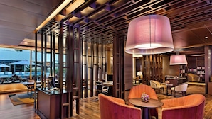 Un hall d’hôtel moderne avec un plancher en bois, un comptoir d’accueil et des espaces aménagés avec des sièges.
