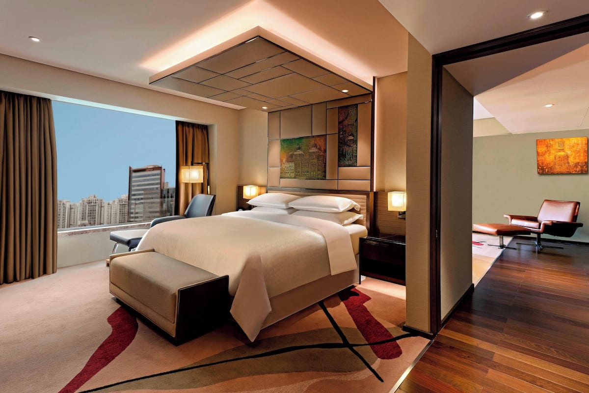 Habitación de hotel moderna con una cama grande, un escritorio, una silla y vistas a la ciudad.