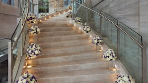 Un magnifique escalier en marbre, doté de rampes en verre et agrémenté de compositions florales à chaque palier.