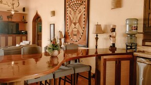 Un coin repas avec une table en bois, des chaises grises, un lustre et un grand tableau abstrait accroché au mur.