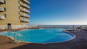A swimming pool with a clear view of the ocean, surrounded by a white fence and a brick walkway. - Beach Front Property in Panama City Beach Florida (Panama City Beach)