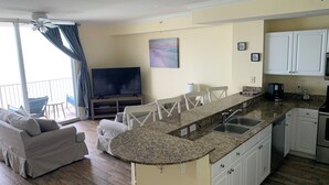 A modern kitchen with granite countertops, white cabinets, and a built-in island with a sink. - Beach Front Property in Panama City Beach Florida (Panama City Beach)