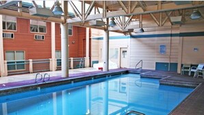 Ein hallenbad mit klarem Wasser, Metallleiter und Fliesenboden.