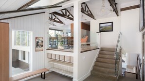 Um interior moderno com escada, um banco e área de refeições com vista.