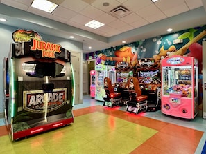 A gaming arcade with various machines, including a 'Jurassic Park' themed one.