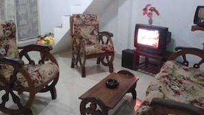 Una sala de estar con muebles de madera, un televisor y una escalera.