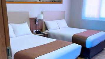 A hotel room with two beds, a nightstand with a lamp, and a painting on the wall.