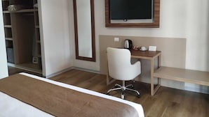 Una habitación de hotel con cama, escritorio, silla, televisor y armario.