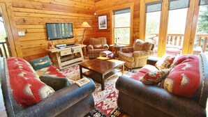 A cozy cabin interior with wooden walls, a TV, a desk, and comfortable seating. - Ashling Ranch - Gorgeous, luxury log home with access to Yellowstone River! (Emigrant)