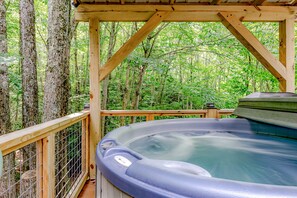 A hot tub on a wooden deck surrounded by trees.