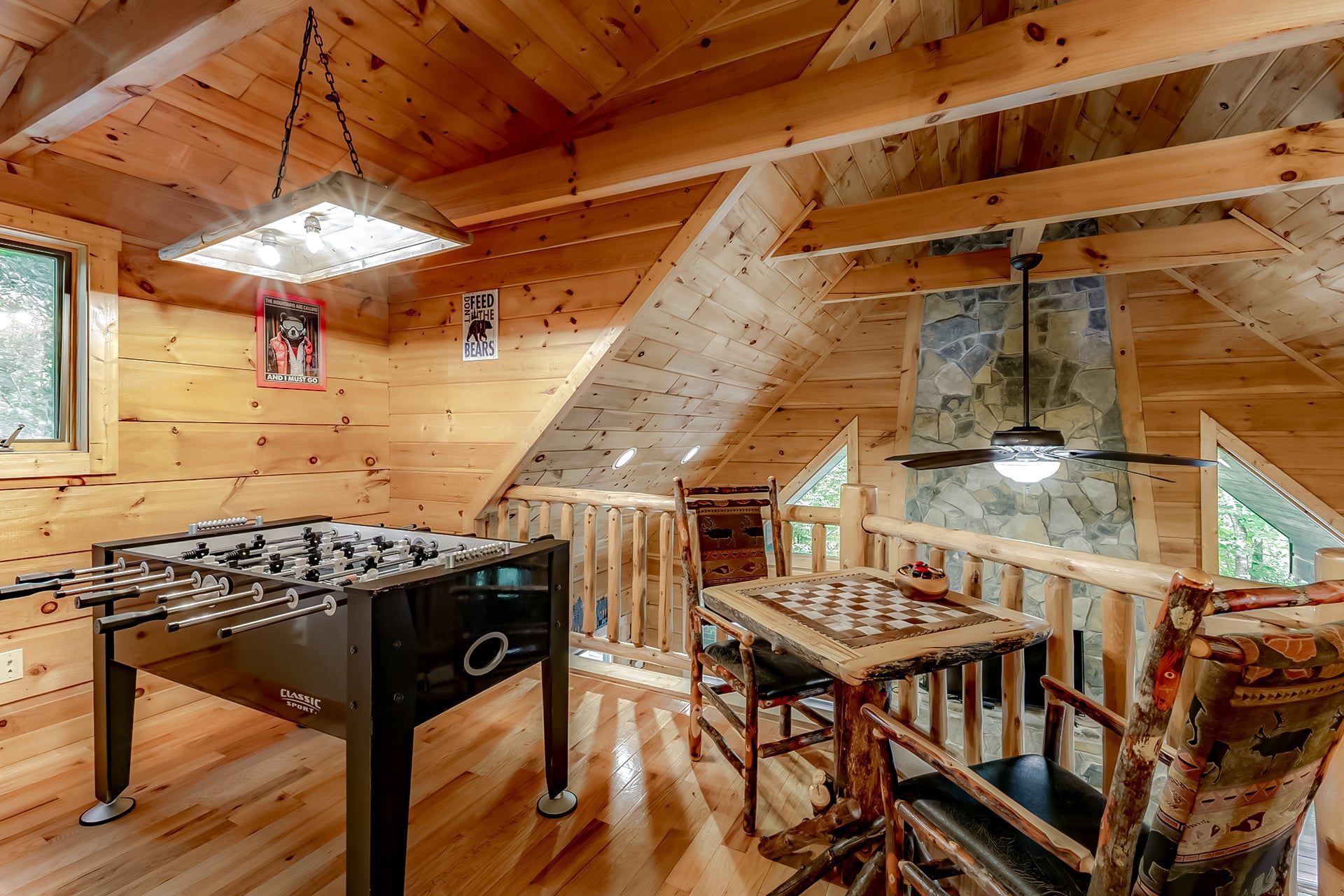 A wooden interior with a foosball table, a chess table, and a ceiling fan.