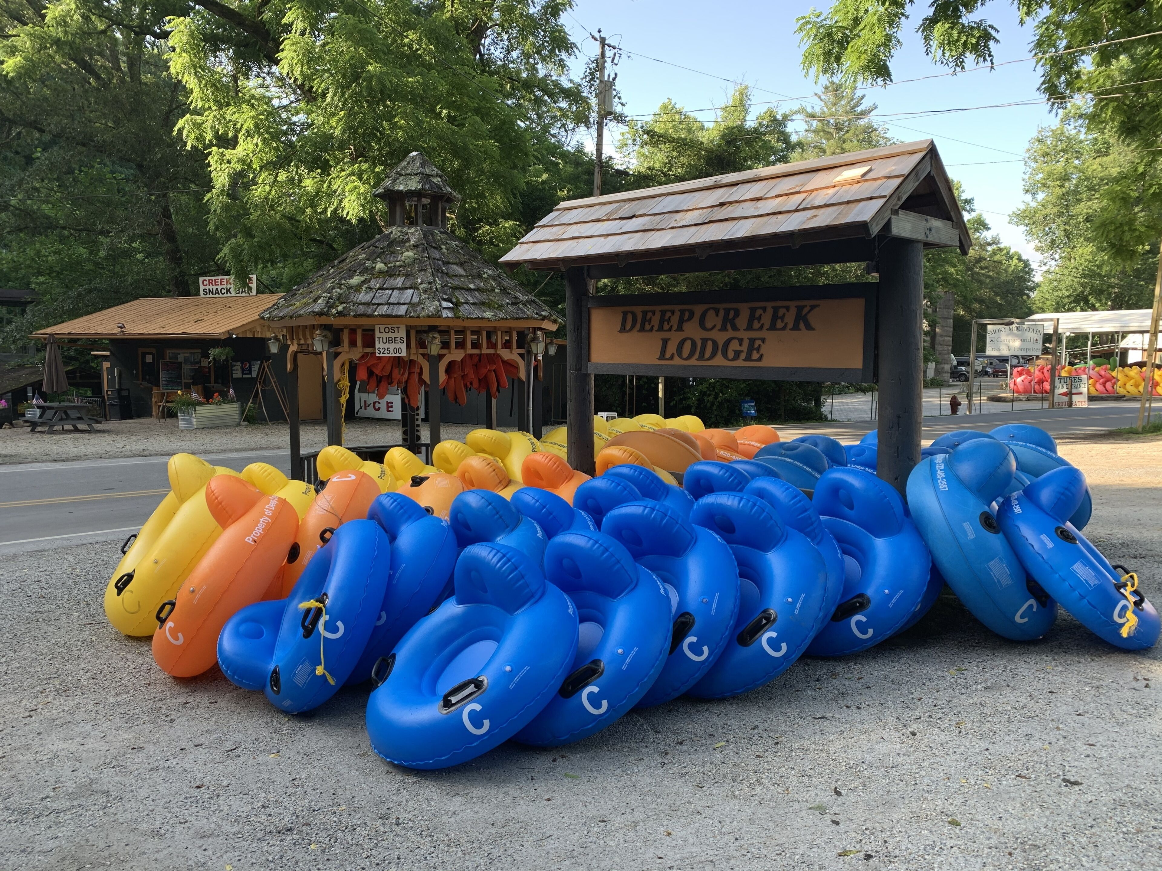 A row of inflatable tubes in various colors, a small gazebo, and a sign for Deep Creek Lodge.