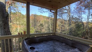 Ein Whirlpool auf einer Holzterrasse mit Blick auf Herbstbäume.