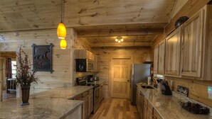 Ein Holzblockhaus-Interieur mit einer Küche, die sich durch Granit Arbeitsplatten, Holzschränke und eine zentrale Kochinsel auszeichnet.