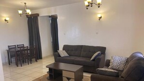 Ein Wohnzimmer mit Sofa, Sessel, Couchtisch und Esstisch.