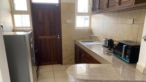 Eine kleine Küche mit Kühlschrank, Mikrowelle, Toaster und Spüle.
