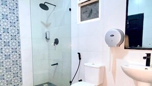 Ein Badezimmer mit Toilette, Waschbecken, Dusche und Spiegel.