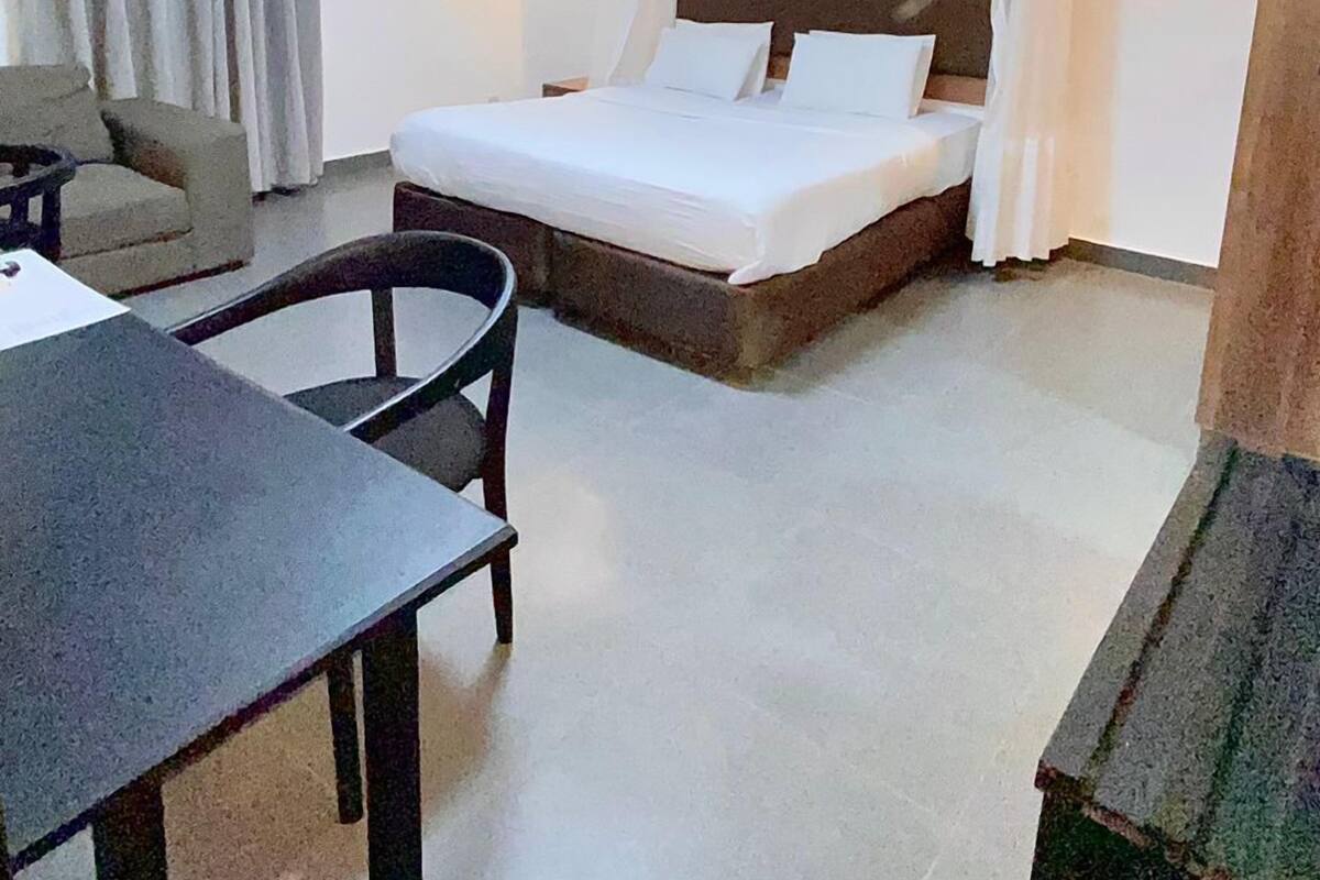 A hotel room with a bed, a desk, a chair, a sofa, and a small table.