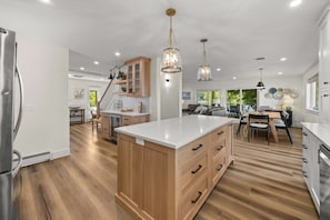 A spacious kitchen with wooden cabinets, a central island, and pendant lighting. - Tranquility on Keuka: Family Retreat with Private Lakefront (Hammondsport)