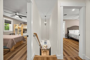 Un dormitorio con una cama litera, un escritorio, una silla, un ventilador de techo y una araña.