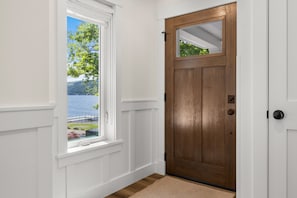 Eine Holztür mit Fensterblick auf einen See und Bäume.