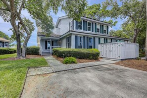A two-story house with a front porch, a garage, and a well-maintained lawn. - Beautiful Lands End Townhome with Spectacular Water Views & Close to Beach (Hilton Head Island)