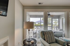 Un salon avec un canapé, une lampe et une vue sur un patio extérieur.