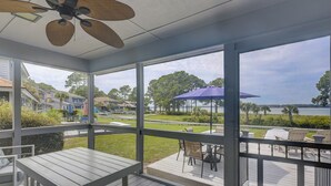 A covered outdoor area with a table and chairs, overlooking a grassy area and a body of water. - Beautiful Lands End Townhome with Spectacular Water Views & Close to Beach (Hilton Head Island)