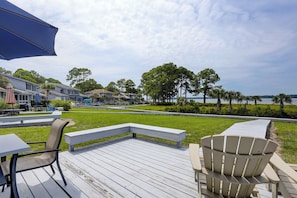 Een terras met buitenmeubilair, uitzicht op een waterpartij en een rij huizen op de achtergrond.