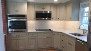 A modern kitchen with grey cabinets, stainless steel appliances, and a wooden floor. - Peaceful, comfortable Cape Cod house close to the shore (North Eastham)
