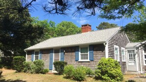 A two-story house with a gabled roof, blue shutters, and a brick chimney. - Peaceful, comfortable Cape Cod house close to the shore (North Eastham)