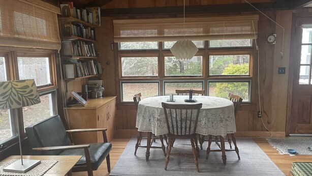 A cozy dining area with a round table, chairs, and a bookshelf. - Peaceful, comfortable Cape Cod house close to the shore (North Eastham)