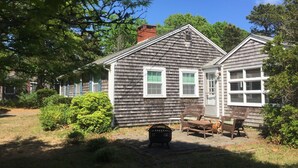 A two-story house with a front porch, a small garden, and a grill. - Peaceful, comfortable Cape Cod house close to the shore (North Eastham)