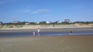 A beach with houses in the background and a person walking on the sand. - Peaceful, comfortable Cape Cod house close to the shore (North Eastham)