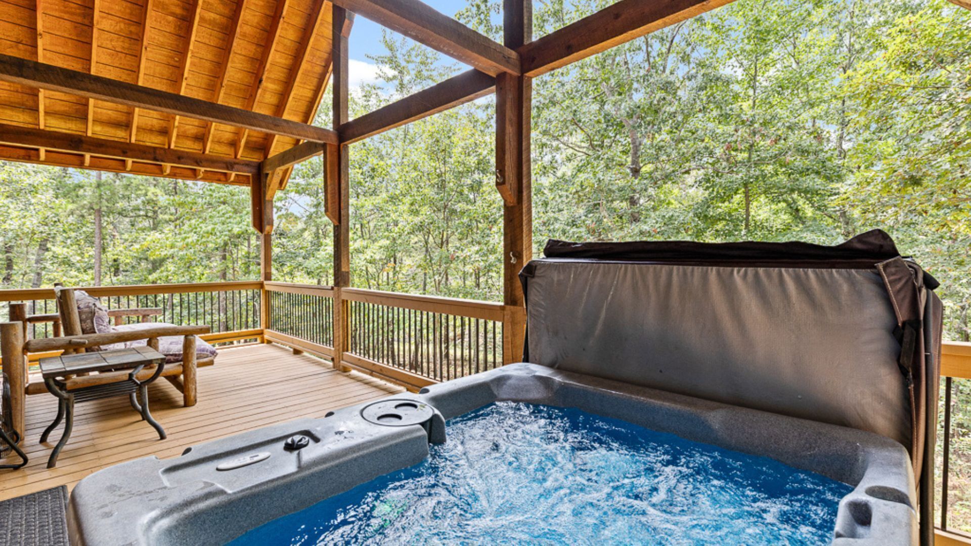 A hot tub on a wooden deck with a view of trees.