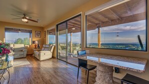 A spacious living room with a large sliding glass door leading to a balcony, a ceiling fan, and a marble countertop.